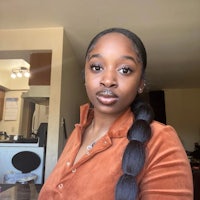 a woman wearing a brown shirt and a braided hairstyle